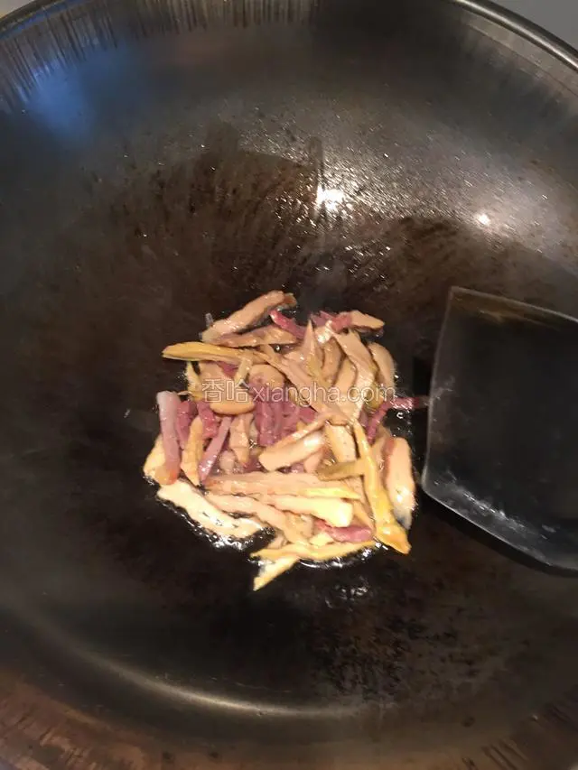 油锅微热时倒入笋丝和火腿丝煸炒