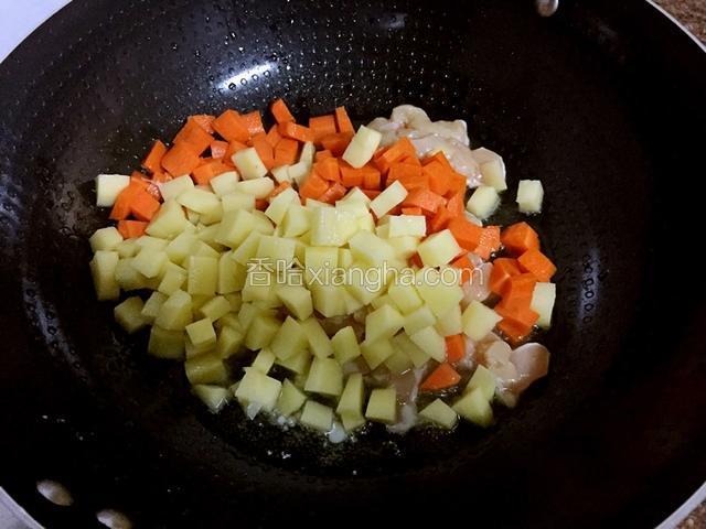 锅中倒入适量的油烧热后放入鸡肉、土豆丁、胡萝卜丁翻炒至鸡肉变色变白