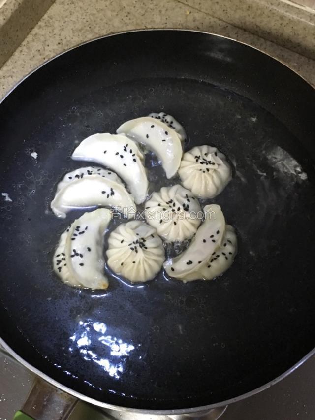在饺子上撒上黑芝麻，盖上锅盖，大火煮。