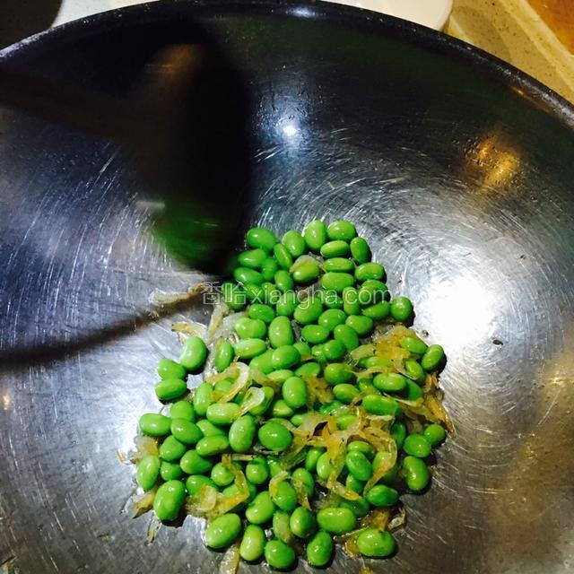 中火热锅，加油烧至八成热，倒入虾皮翻炒几下，煸出香味后加入毛豆翻炒。