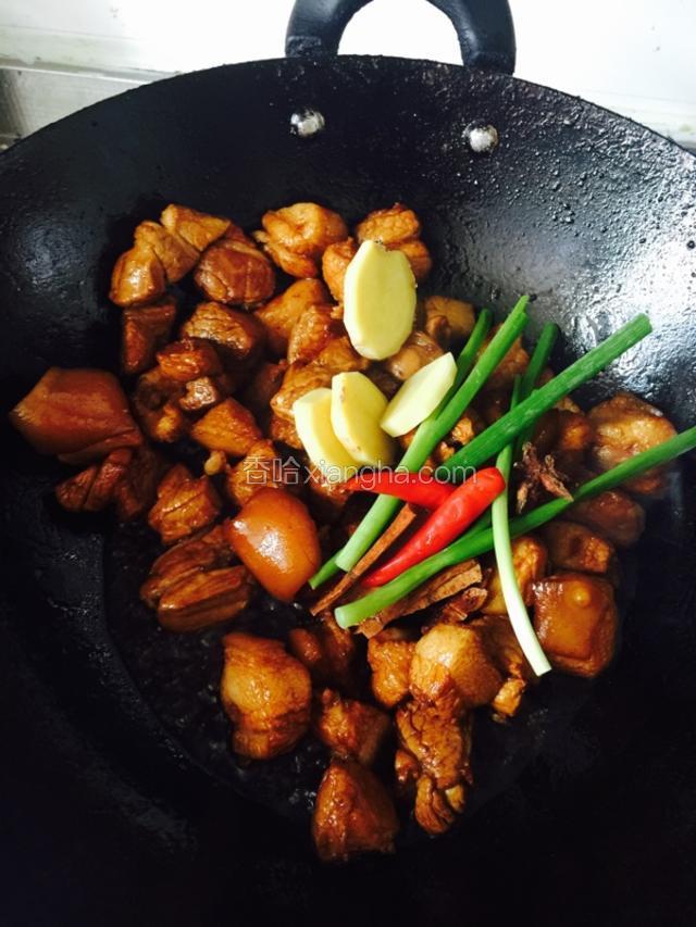 待泡沫快没了时，放入肉块翻炒，炒匀后加料酒、老抽、葱、姜、小红椒等调料放入继续炒