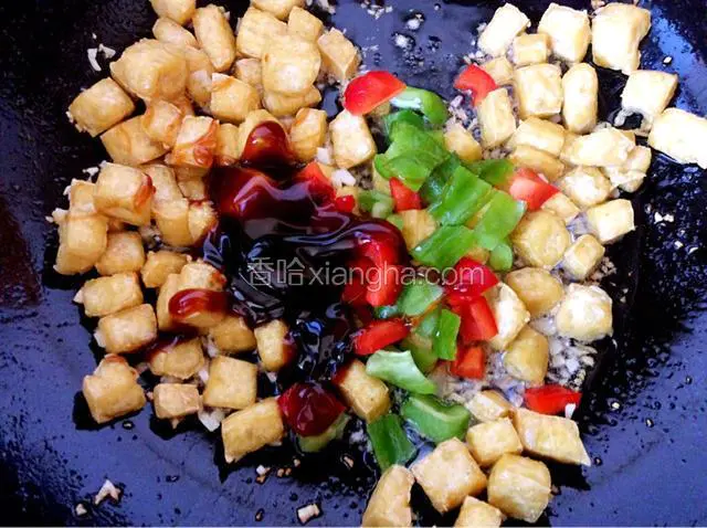 把炸好的豆腐和青红椒丁放入锅中，加适量的蚝油翻炒一下。
