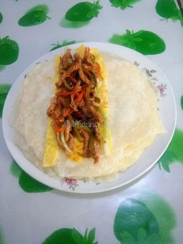 将饼上摆上黄瓜丝，鸡蛋饼条和肉丝卷起来即成。喜欢吃大葱的也可以加葱。