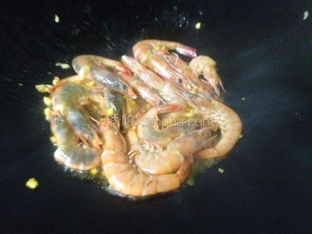 热锅冷油下蒜沫爆香,倒入腌好的虾.