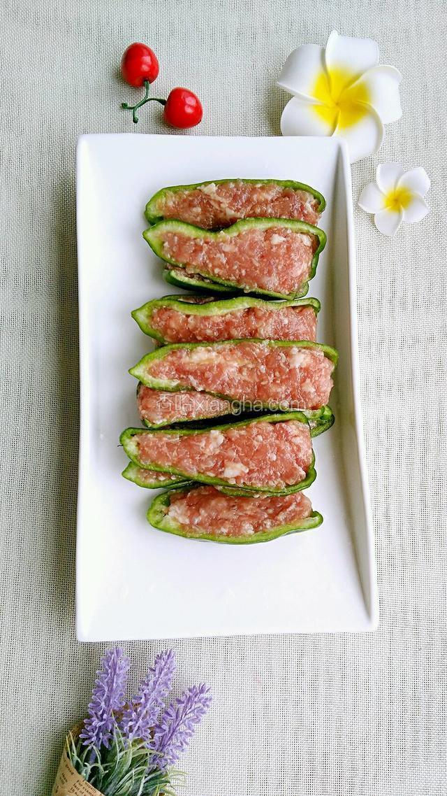 用勺子将肉末调入青椒压紧。