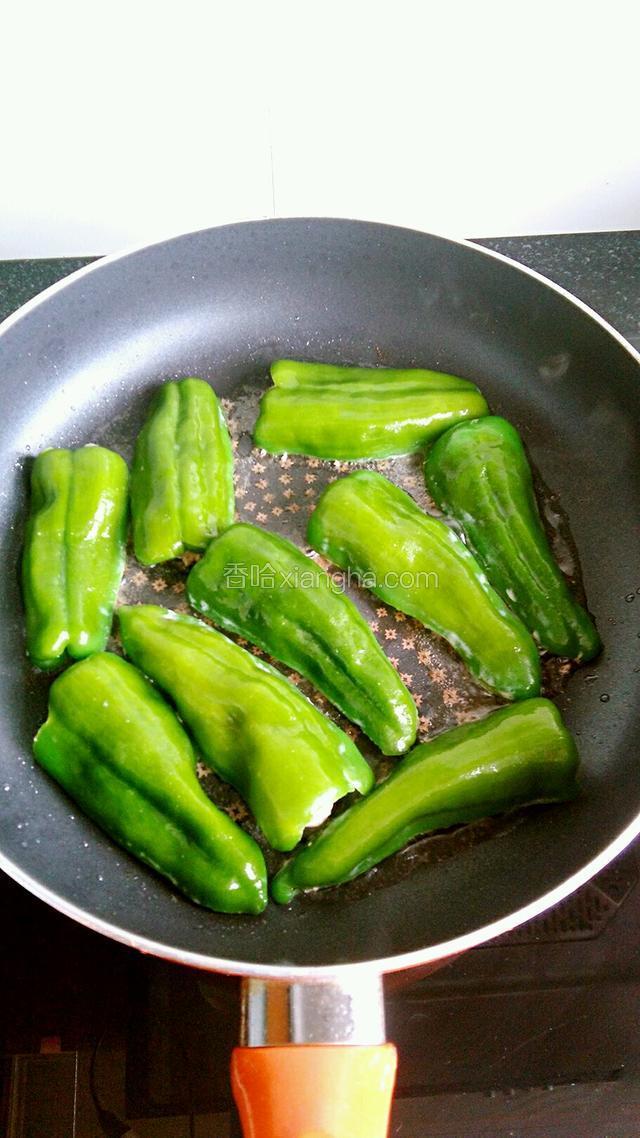 热油锅，放入包了肉的青椒，小火煎。