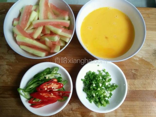 西瓜皮去掉绿色皮和多余瓜瓤切片，将鸡蛋打入碗中，用筷子搅匀，青红椒整个切斜刀，葱切成葱花