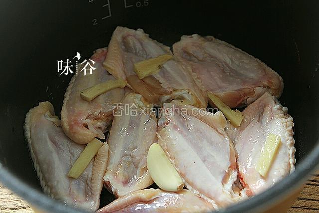 按下煮饭键，倒入适量油，放姜片，蒜，鸡翅皮朝下，盖盖煎煮一会。