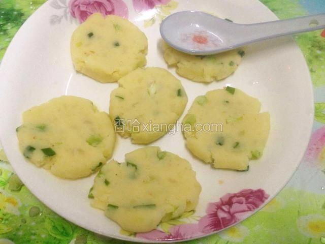 调羹沾水,将土豆球压成饼状.