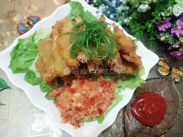 炒好的洋葱红椒丁放在装虾的盘里，可以就着吃，也可以蘸番茄酱一起食用，用大葱丝装饰下，炸好的虾外脆里嫩，趁热吃，味蕾的享受！