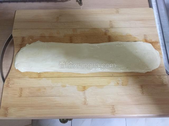案板上抹色拉油，将面团按扁成图中长条状。