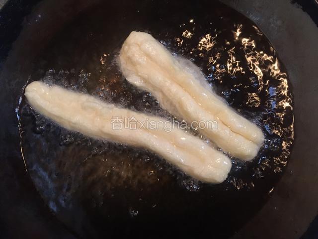 锅中倒入宽量油，油温五成热时放入加工好形状的油条胚，小火炸制。