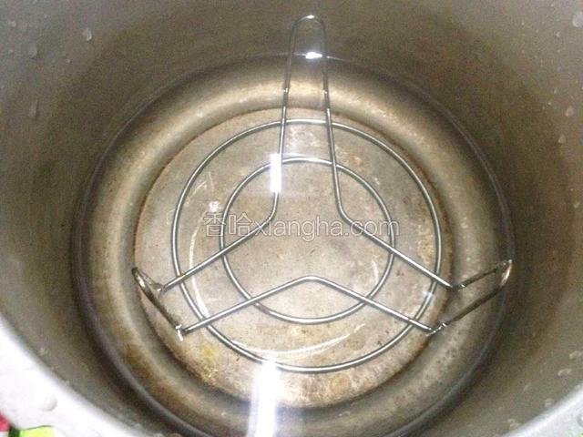 取一高压锅,放入三角蒸架,蒸架角朝上,注入清水.