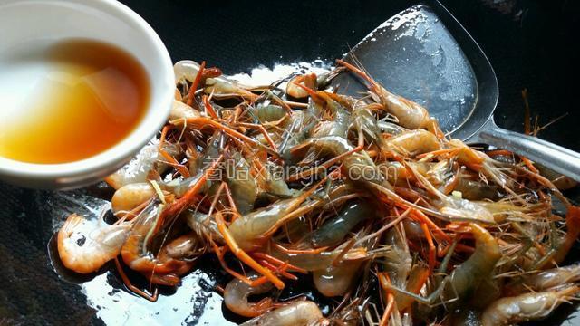 放入河虾翻炒至开始变红，烹入料酒。