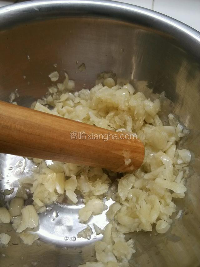 先将独蒜拍扁，然后装在碗中，用擀面杖捣碎