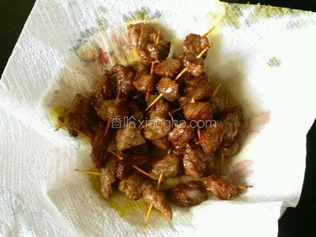 把捞出的牛肉串放在吸油纸上吸油。