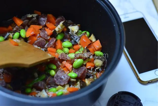 在饭煲中倒入炒好的食材搅均匀。