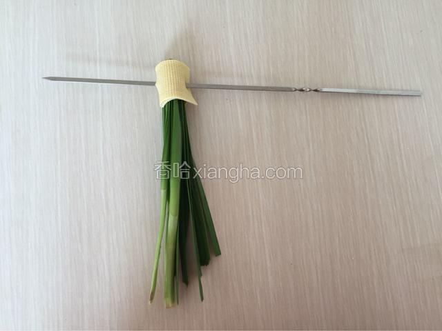 取三到四颗韭菜对折用豆皮卷起来穿去烤签