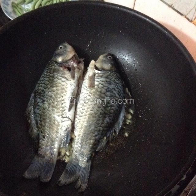 下鲫鱼煎制，一面煎好翻过来煎另一面。