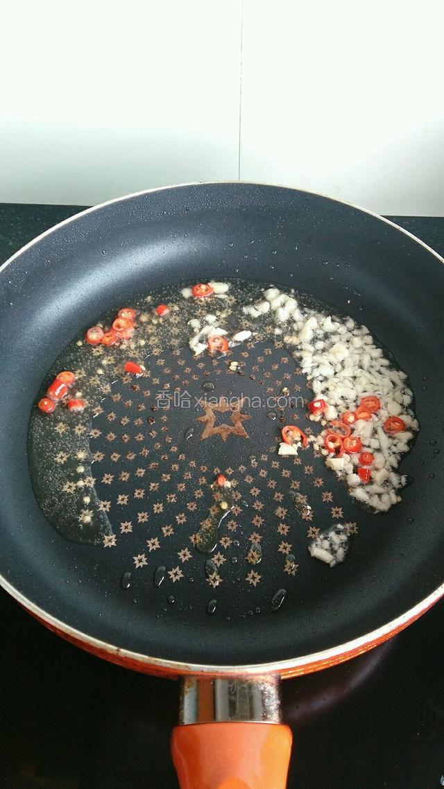 炸过茄子的油倒出来装到耐热的容器中（以后炒菜用，尽快用完以防变质），锅中留适量油，倒入红米椒和蒜末，小火煸香。