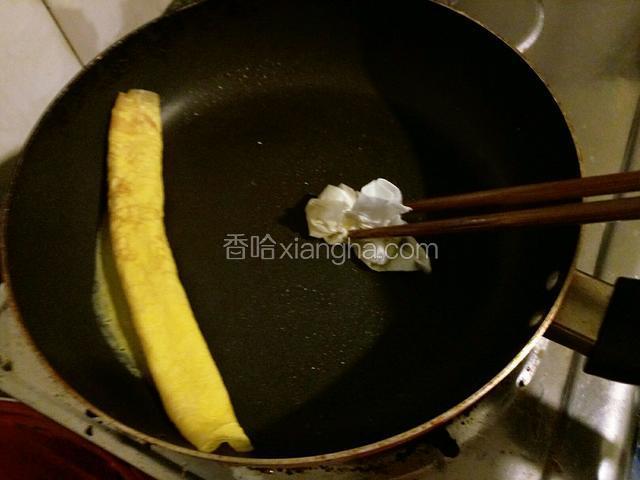 卷好放锅的一边就不用管它了，用筷子夹刚才的纸巾沾油在空的地方抹一层油。