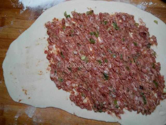 肉馅均匀的铺在面饼上，窄的那头留出1/4不放肉馅。