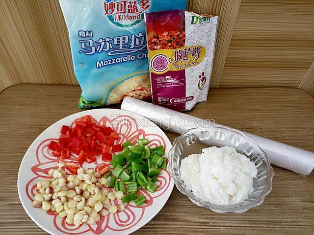 准备材料。玉米粒提前焯水，青椒甜椒切丁，剩米饭适量，保鲜膜或保鲜袋。预热烤箱上下火200度。