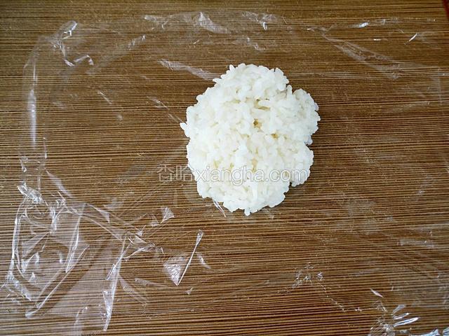 保鲜膜撕下一块稍大点，放入一块米饭。米饭不要太多，做成手掌大小最好。