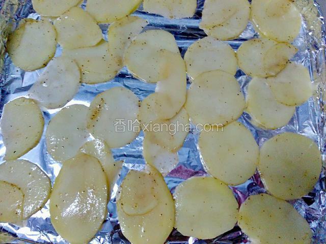 烤箱180℃提前预热5分钟。将土豆片均匀的铺在包有锡纸的烤盘上。