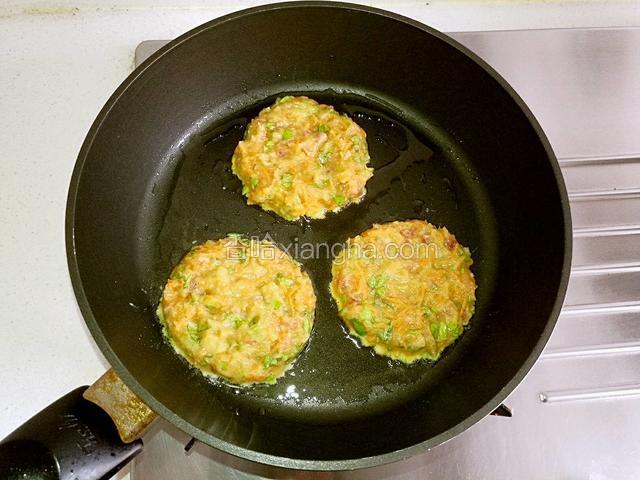 用勺子舀一大勺土豆鸡蛋糊，倒入锅里，摊成小饼，一个锅做三个，然后用小火慢慢地烙。