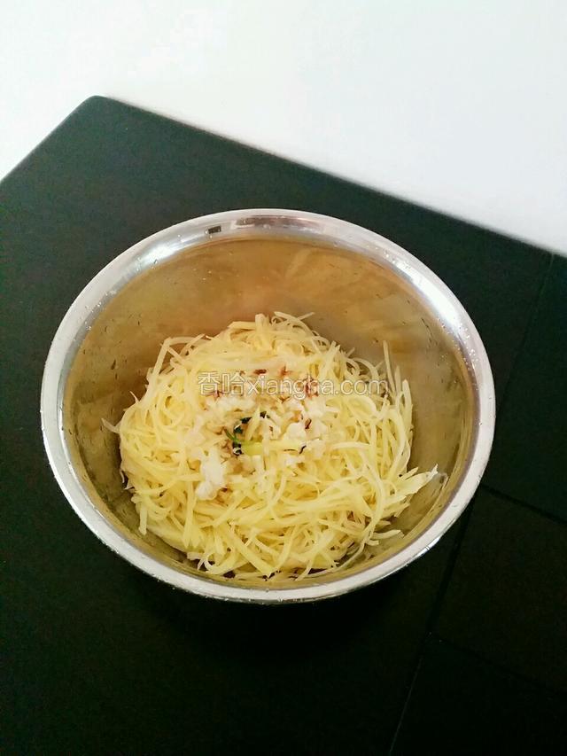 将晾干后的土豆丝倒入容器中，然后将爆炒好的葱姜蒜倒入其中，搅拌均匀