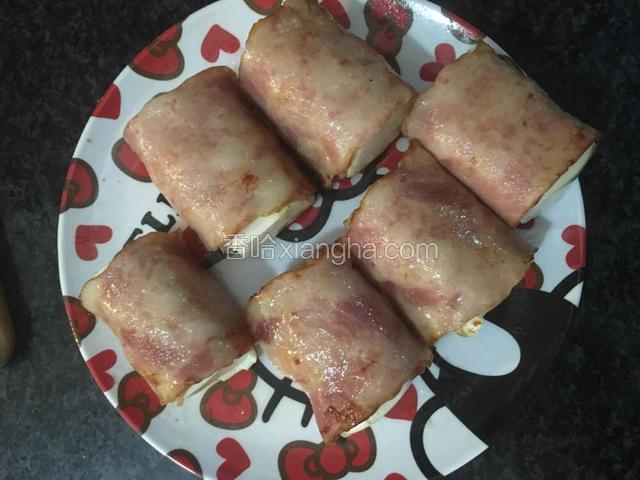 用培根把豆腐卷起来，淀粉用水调成糊状封口

锅内倒入适量油，把培根豆腐卷煎至微黄