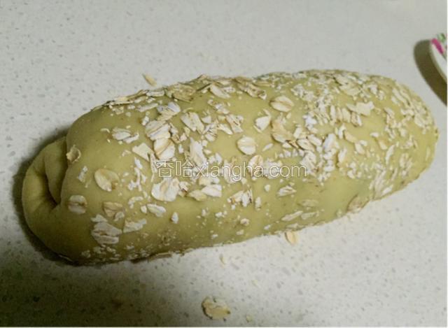 顺着一头慢慢卷起来，在成形的面包胚上滚上一层麦片。