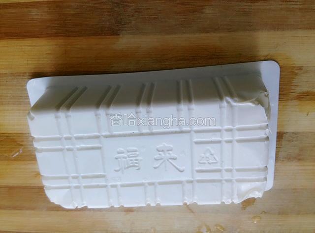 再把内酯豆腐倒扣过来，对角线的顶端切小口，让空气进去，这样就容易把盒子慢慢地拿下来