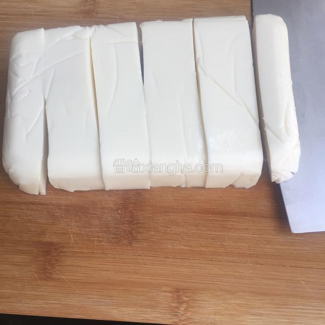 取出保鲜盒，倒扣倒出椰奶冻，揭开保鲜膜，切条再切块。