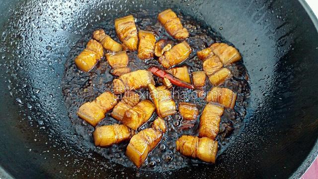 调入适量的生抽、老抽和料酒，再滴入少许的白醋，翻炒均匀至五花肉上色。
