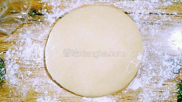 松弛20分钟的水油皮  取出 案板洒少许的面粉  把面团放上  用手压下  用擀面杖  擀成边上薄中间厚（切忌   取出的水油皮  用手揉）