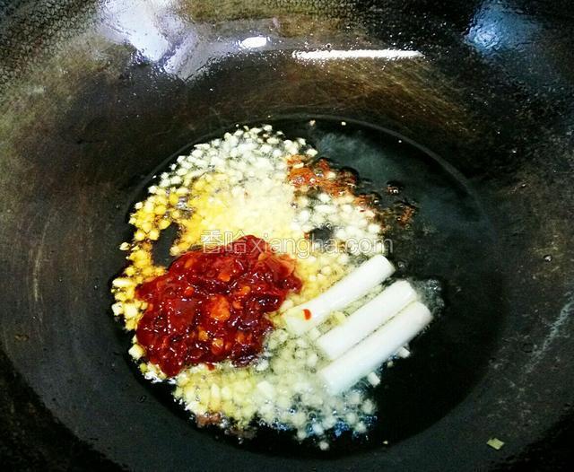 将大葱段、花椒粒、姜蒜粒、郫县豆瓣依次放入锅中炒