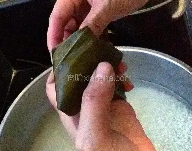 盖好以后把多余的粽叶向一侧折过去。