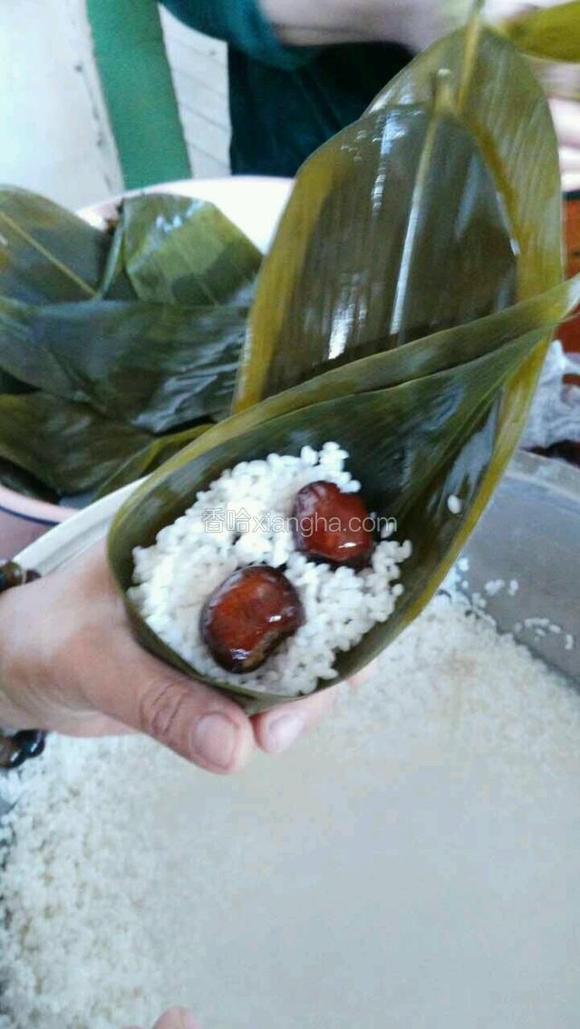 在折好的粽叶里加入江米蜜枣，红枣或葡萄干