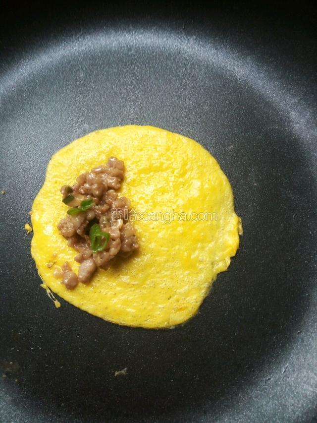 再开小火，待蛋液稍凝固后，在一边加入炒好的肉馅。