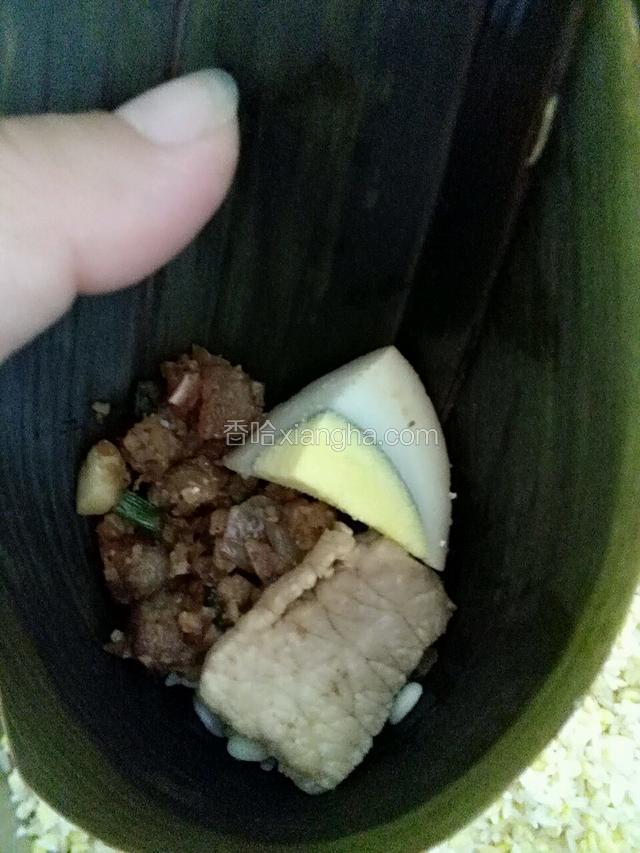 取两叶粽叶卷成圆锥形，先放点拌好的大米和绿豆，在放入陷料