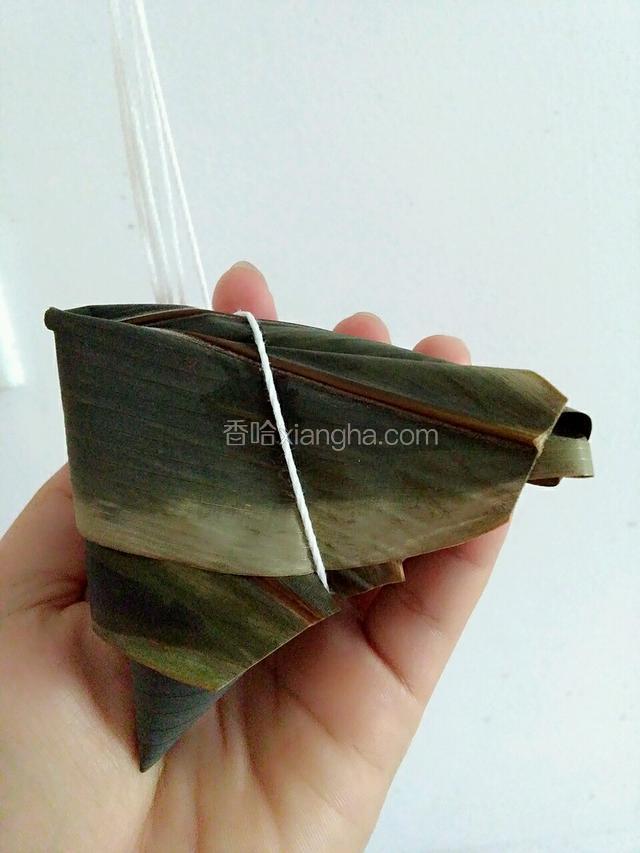 用剪刀剪去多余的粽叶，用棉线有下往上绕过去打死结