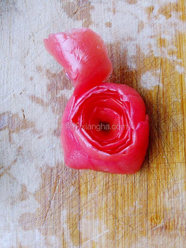 将西红柿皮从一头卷起，皮面卷里面。