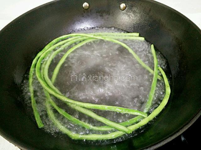 锅里水烧开，加几滴油，放入豆角焯水。