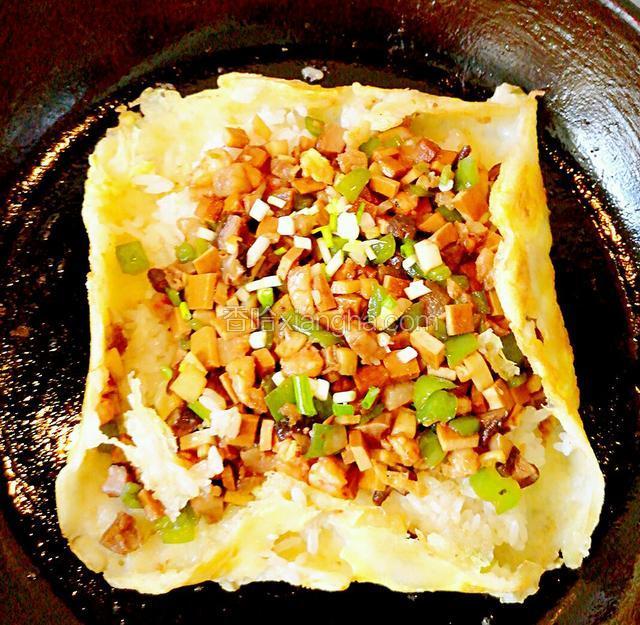 将炒好的料铺在糯米饭上，压实后，四边包起