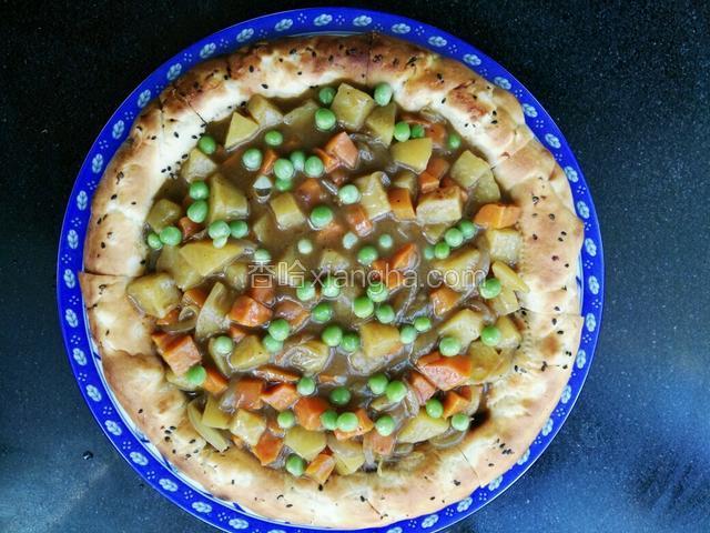 将炒好的咖喱酱倒在馕饼子上，撒上之前煮熟的青豆