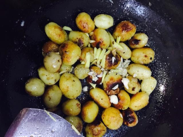 煎焦黄后加入生姜、大蒜、辣椒爆炒，撒少许辣椒粉上色！