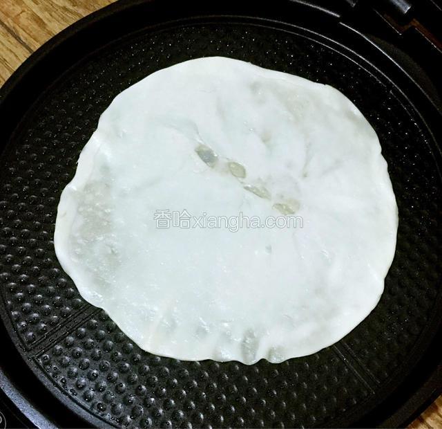 在预热好的电饼档下盘涂抹适量植物油，将面饼平铺放入，盖上盖子选择煎饼/煎蛋档。