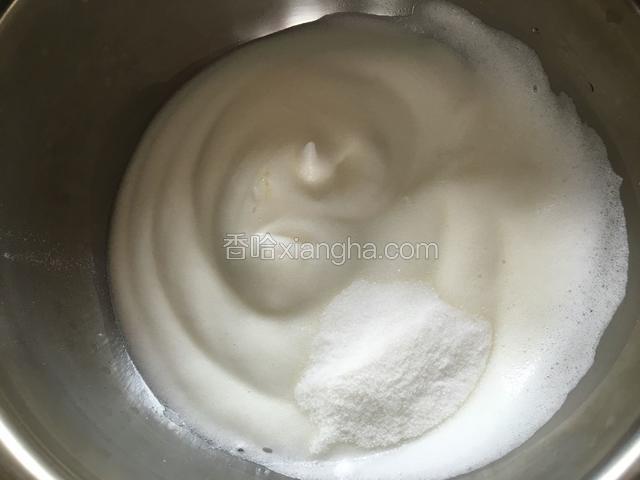 再继续搅打，到蛋白比较浓稠，表面出现纹路的时候，加入剩下1／3的糖。